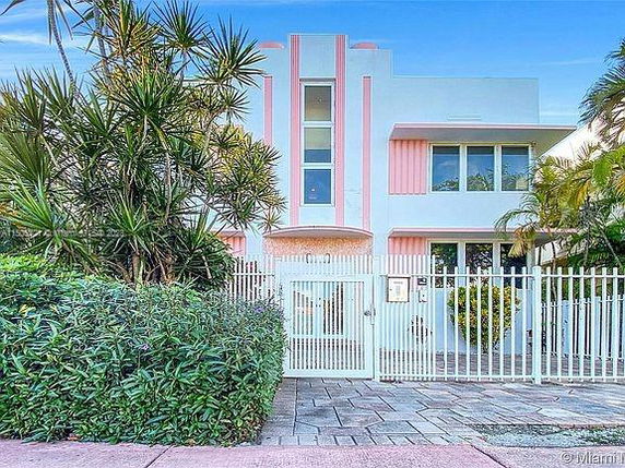 Front view of a two-story house with a gated entrance and pink accents.