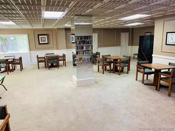 Interior view of a room with tables, chairs, and bookshelves, suitable for recreation or social activities.