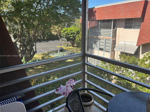 View from a balcony showing adjacent building and parking area.