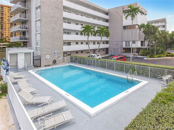 Outdoor swimming pool area in front of a multi-story building.