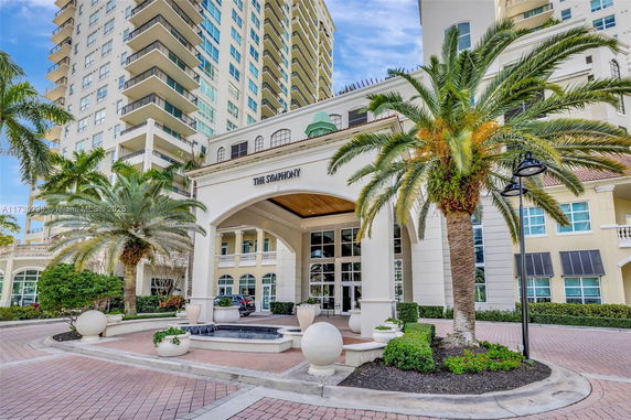 Front view of a multi-story building with balconies and an arched entrance.