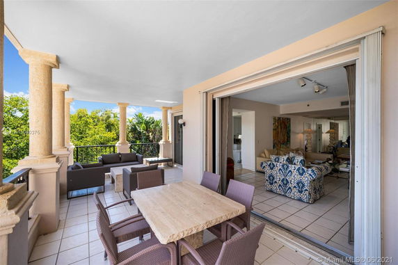 Outdoor patio connected to an indoor living area with a view of surrounding greenery.