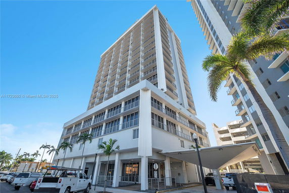 Front view of a tall residential building with multiple balconies.