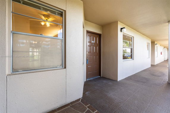 Exterior view of a building corridor with windows and a brown door.