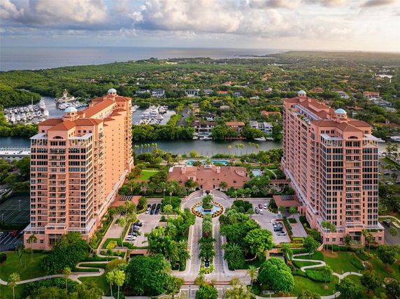 Aerial view of two tall residential buildings with a circular entrance and landscaped grounds, surrounded by lush greenery and waterways.