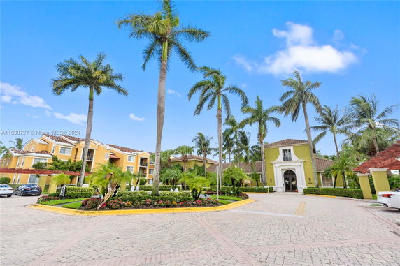 Front view of a residential complex with palm trees and a decorative entrance.