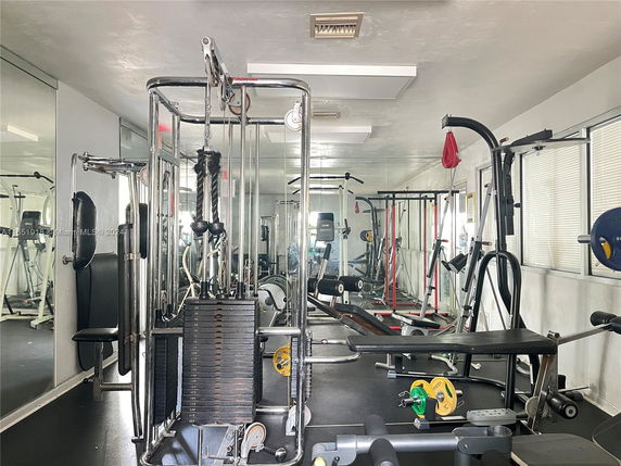 Room with various gym equipment including weight machines and cardio machines.