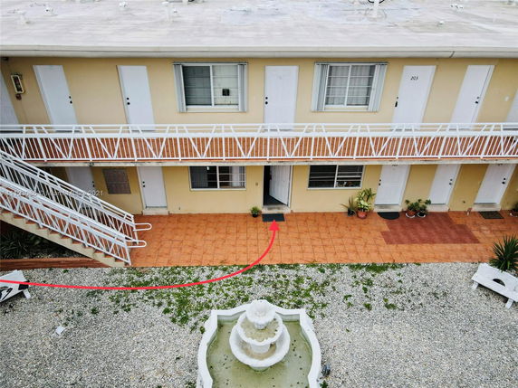 Front view of a two-story building with stairs and multiple doors.