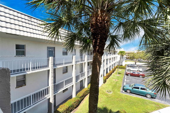 Front view of a multi-story building with balconies and a palm tree in the foreground.