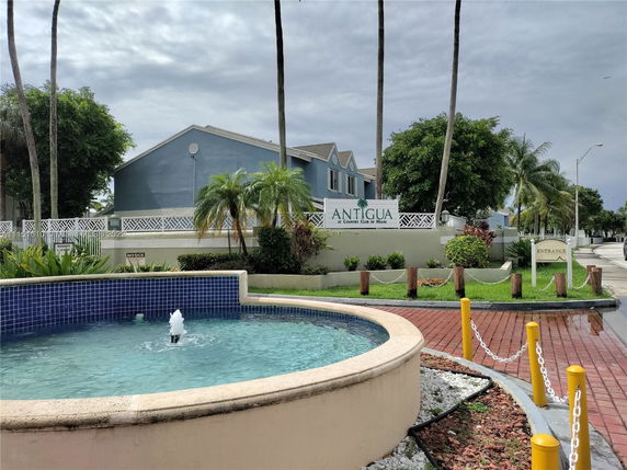 Front view of a residential building with a blue facade and a decorative fountain in the foreground.