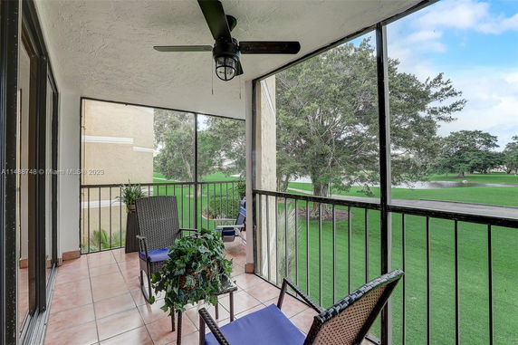 Balcony view overlooking green grass and trees with outdoor seating.