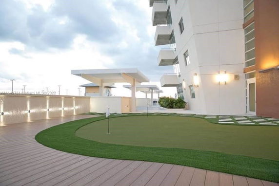 Rooftop area with artificial grass and golf putting green beside a modern building.