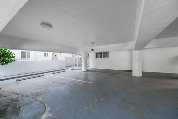 Covered parking area with a concrete floor and supporting pillars.