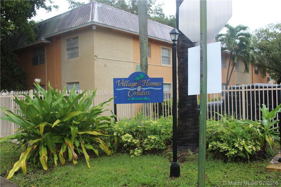 Front view of a two-story condominium building with a sign reading 'Village Homes & Condos'.