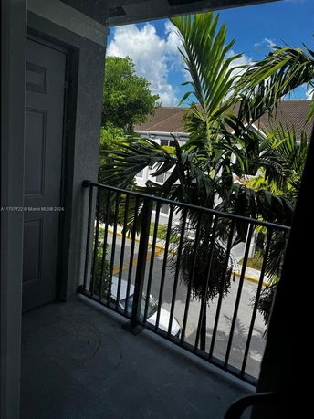 View from a balcony showing trees, a nearby building, and a street below.