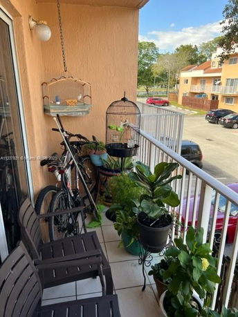 Balcony with plants, bird cages, and a bicycle.