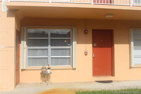 Front view of a building entrance with large windows and a red door.