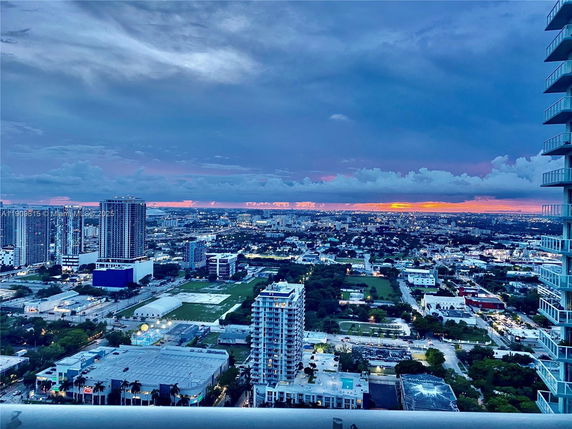 Wide angle view of a cityscape with buildings and sunset in the background.