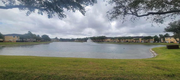 View of a pond surrounded by trees and houses.