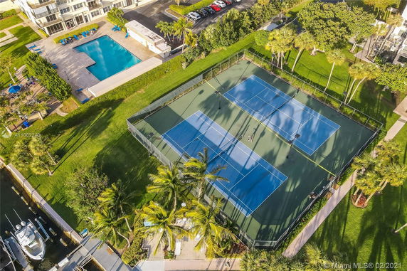 Aerial view showing a swimming pool, tennis courts, and a building with parking lot.