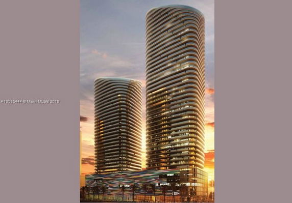 Front view of two modern high-rise buildings with a unique wave-like design.