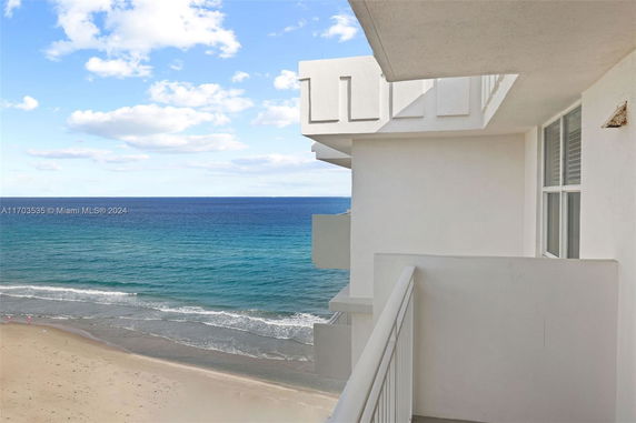 Balcony view from a building overlooking the ocean and beach.