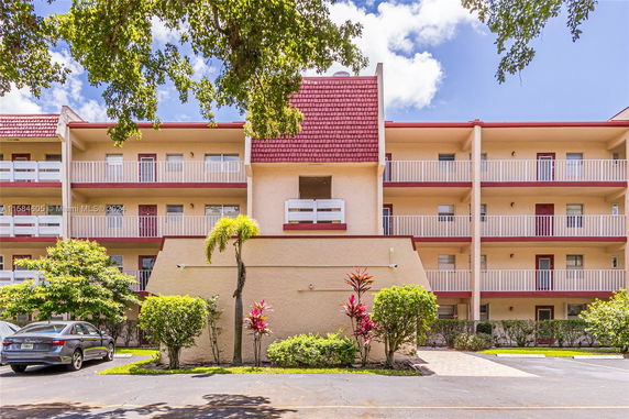 Front view of a multi-story building with balconies and a sloped roof.