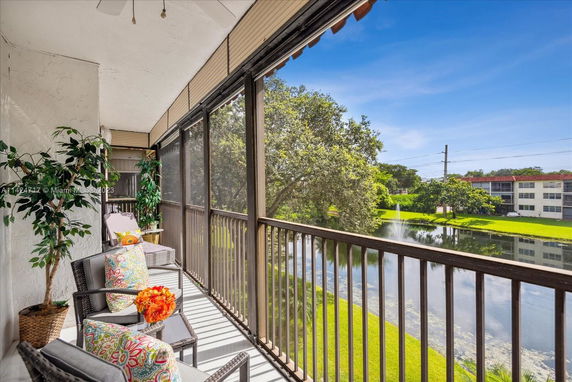 Balcony view overlooking a pond and surrounding buildings with greenery.