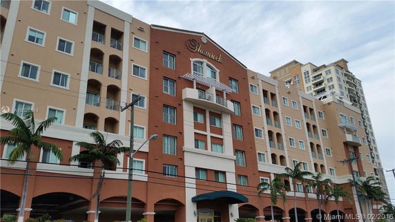 Front view of a multi-story apartment building with a mix of beige and red exterior walls and balconies.