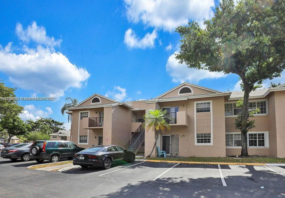 Front view of a two-story apartment building with a parking area in front.