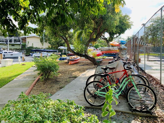 Outdoor area with bicycles and kayaks near a building, surrounded by trees.