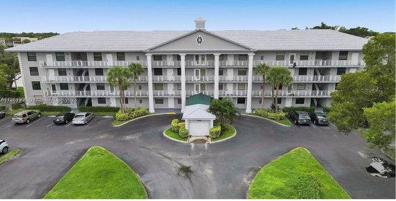 Front view of a multi-story residential building with balconies and a parking area.