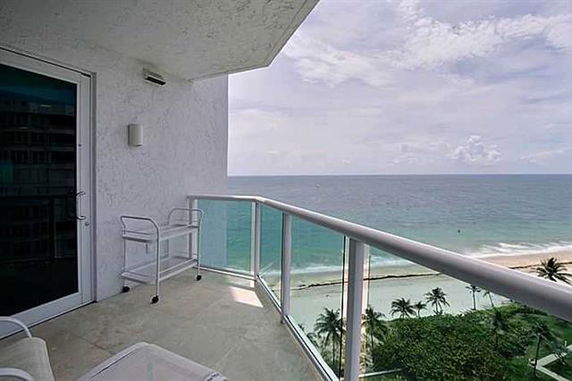 View of the ocean from a balcony with glass railing.