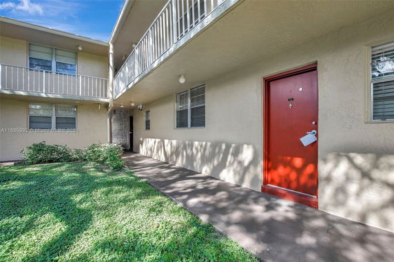 Front view of a two-story building with balcony and red door.