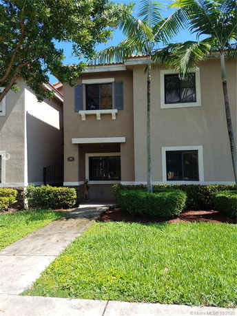 Front view of a two-story house with a paved walkway leading to the entrance.