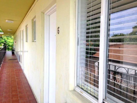 Exterior corridor of a residential building with doors and windows.