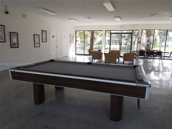 Room with a billiards table and seating area with large windows.