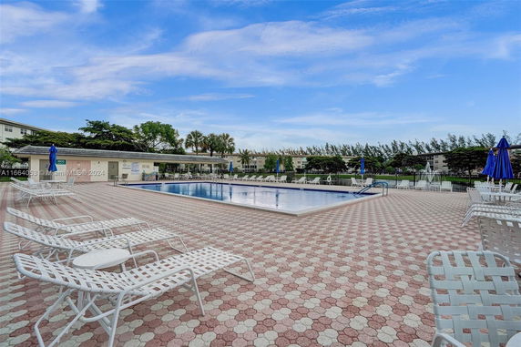 Outdoor swimming pool area with lounge chairs and umbrellas.