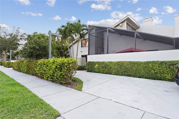 Front view of a multi-story house with a screened patio and white exterior walls.