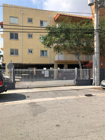 Front view of a multi-story residential building with a gated entrance.