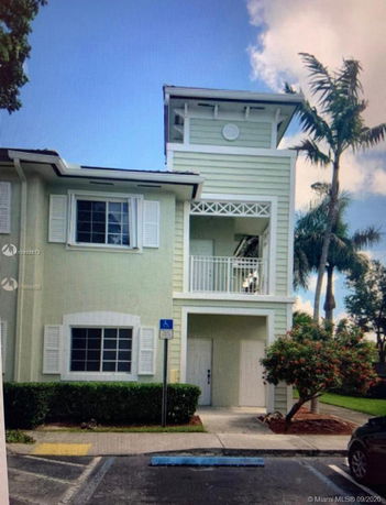 Front view of a two-story house with a tower-like feature and balcony.