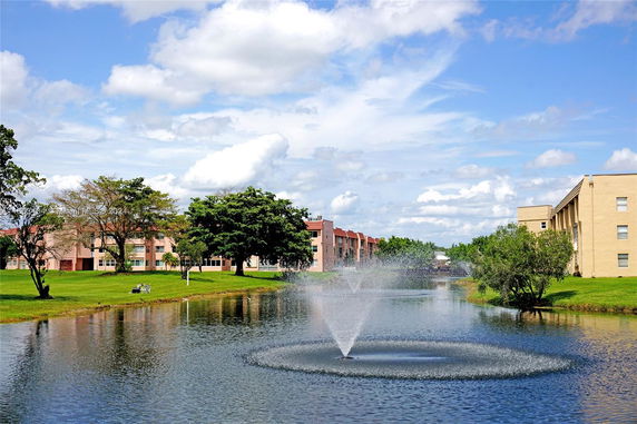 View of buildings near a lake with a fountain in a landscaped area.