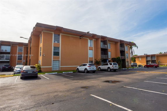 Front view of a multi-story apartment building with parking spaces.