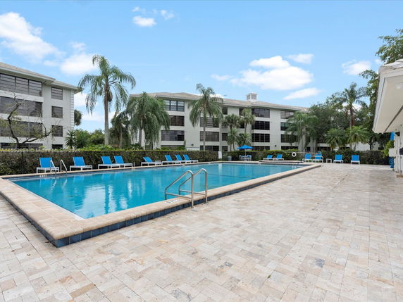 Outdoor swimming pool area with lounge chairs and surrounded by buildings.