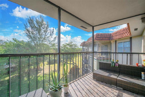 View from a screened balcony with outdoor seating and potted plants.