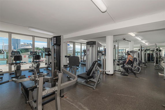 Interior view of a fitness center with various exercise equipment and large windows.