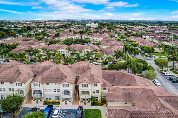 Aerial view of a residential neighborhood with multiple houses featuring brown roofs and some palm trees within the area.