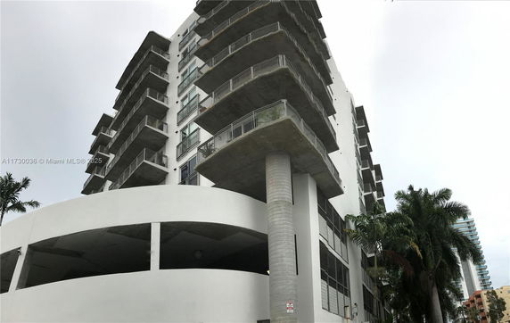 Front view of a multi-story building with protruding balconies.