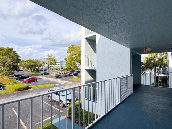 Outdoor parking area with multiple vehicles and visible adjacent buildings.