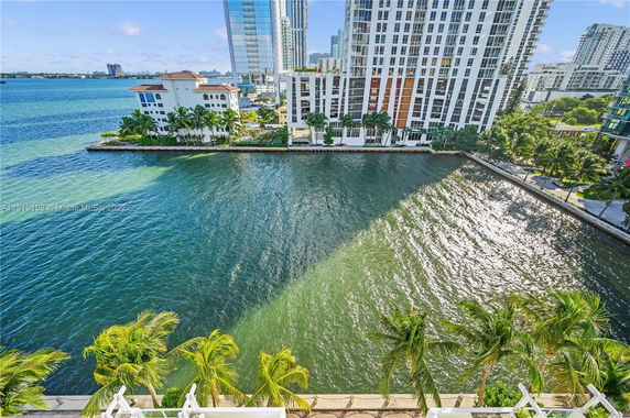 Panoramic view of waterfront buildings and palm trees.